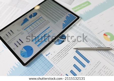 On statistical reports lies a tablet with charts on the screen