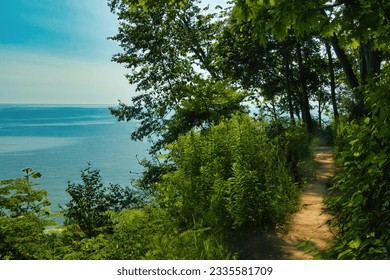 On a Summer day, the view of Lake Michigan from along a dirt hiking trail on a forested bluff near Milwaukee, WI.