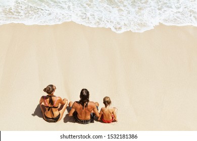 On Sunny Beach Happy Kids With Parents Have Fun, Sit On White Sand See At Sea Surf With Foam And Splashes. Top View. Active Children Lifestyle, Summer Family Vacation Travel On Tropical Family Resort.