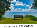 On a sunny Summer day, an empty bench faces Lake Michigan from atop a wooded bluff near Milwaukee, WI.