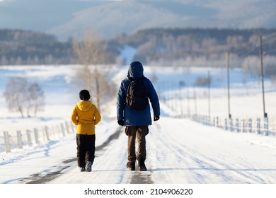 On A Sunny Winter Day, Father And Son Are Walking Along A Wide Road