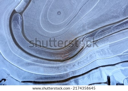 On surface of frozen puddle, pattern of curved lines.