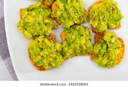 On table in cafe there is plate with traditional Mexican snack - guacamole sandwich. Salty and savory light repast for beer