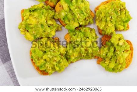 On table in cafe there is plate with traditional Mexican snack - guacamole sandwich. Salty and savory light repast for beer