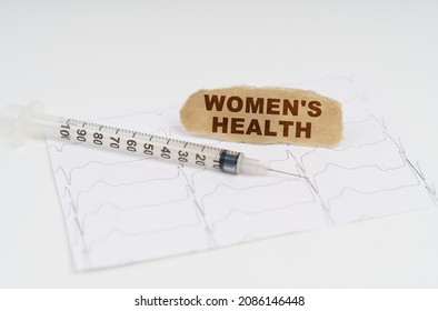 On The Table Is A Cardiogram, A Syringe And Paper With The Inscription - WOMENS HEALTH