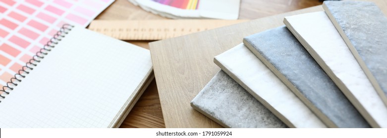 On table is color scheme and samples with color. Selection color laminate and ceramic tiles for repairs kitchen. Color combination in apartment. Coordination choice finishing materials with customer