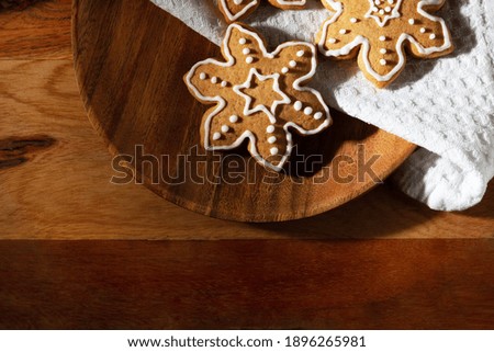 On the table is a delicious traditional ginger cookie with icing sugar in the shape of snowflakes.