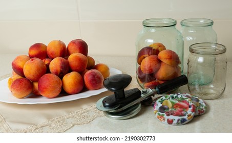 On The Table Is A Dish With Peaches, Jars For Home Canning, Lids For Jars And A Key For Canning