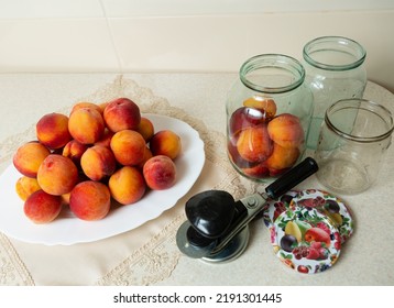 On The Table Is A Dish With Peaches, Jars For Home Canning, Lids For Jars And A Key For Canning