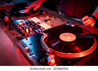 On The Table, The DJ Is Playing A Record Using Two Vinyl Turn Table Players Playing Songs In Succession.