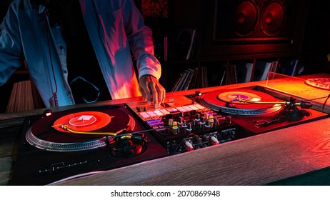 On The Table, The DJ Is Playing A Record Using Two Vinyl Turn Table Players Playing Songs In Succession.