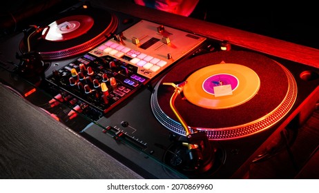 On The Table, The DJ Is Playing A Record Using Two Vinyl Turn Table Players Playing Songs In Succession.