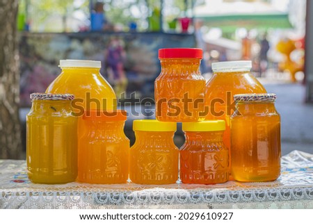 On the table are glass jars and plastic containers filled with Bashkir bee honey and ready to be sold at the honey fair 