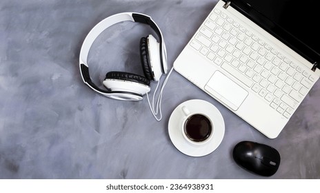 On a table on a gray background is a laptop and a white cup of coffee and a computer mouse, headphones, coffee break concept, office work, online learning, webinars.  Top view, flat lay. - Shutterstock ID 2364938931