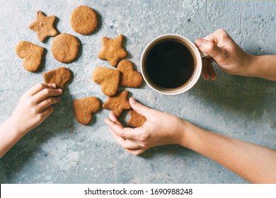 On The Table Are Homemade Gingerbread Cookies. Children's Hand Dragged A Cookie. The Adult's Hand Holds A Coffee Mug And Also Takes One. Family Breakfast Concept.