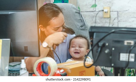 On The Table In The House, The Mother Holds The Child And Uses The Scanner To Point  At The Child. Work Form Home And  Sell Online Concept.