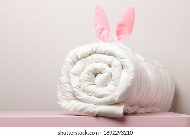 On the table lies a folded warm duvet with Easter bunny ears. Blanket for the bed. Copy space.