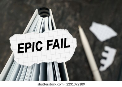 On the table is a notebook on which lies a piece of torn paper with the inscription - Epic Fail. The pen lies outside the sharpness zone.