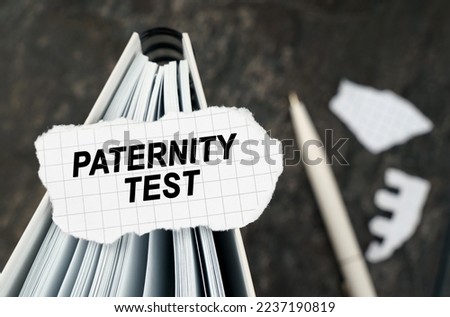 On the table is a notebook on which lies a piece of torn paper with the inscription - Paternity Test. The pen lies outside the sharpness zone.