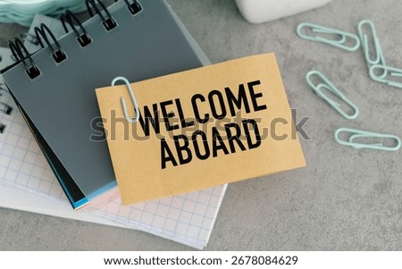 On the table are paper clips, note paper with text - Welcome aboard
