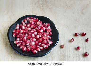 On the table are pomegranate fruits in a dark glass plate.