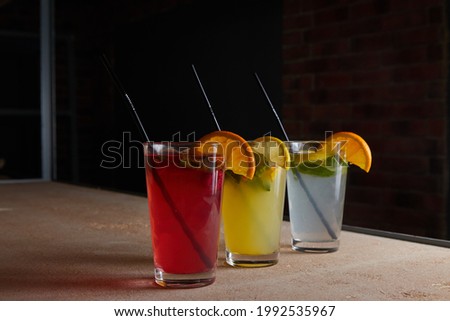 on the table, soft drinks, various cocktails, a glass with a straw and a slice of lemon, a blurred background