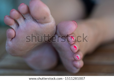 on a table are some dirty feet of a woman with lacquered toenails
