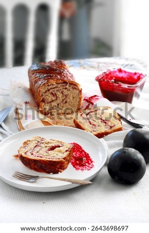 On the table, there is a bread cake made from red plums; babka.