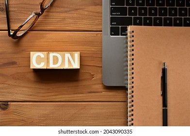 On the table there is a word cube lined CDN with laptop computers and glasses. It is an abbreviation for the word Content Delivery Network.