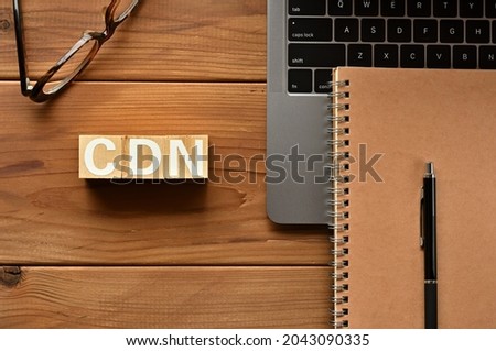 On the table there is a word cube lined CDN with laptop computers and glasses. It is an abbreviation for the word Content Delivery Network.
