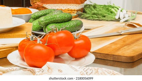 On The Table Are Tomatoes, Cucumbers, Carrots, Cheese, Bread In A Basket, Herbs, Dill, Green Onions, A Knife On The Board