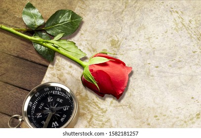 On the table top is a compass, a map, and a red rose. All objects are shown in close-up. - Powered by Shutterstock