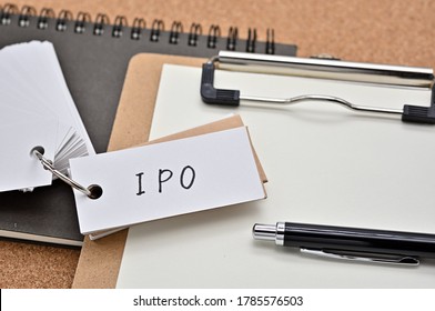 On top of the notebook and clipboard is a wordbook and pen with the word IPO written on it. It means Initial Public Offering.