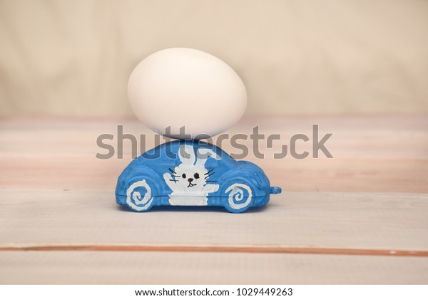 On a toy car there is\
a chicken egg. On the door of the car the Easter rabbit is\
depicted. Easter motive.