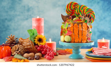 On Trend Thanksgiving Candyland Novelty Drip Cake With Colorful Fall Leaves And Cornucopia Table Setting.