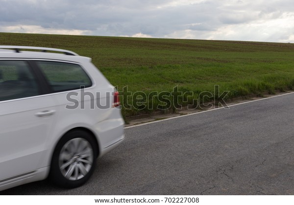 on a very sunny day in august in south germany you\
see driving car on a road  beside green fields with contrastful\
cloudy sky