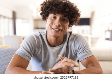 On video call, Smiling young man sitting indoors, enjoying casual conversation with friends, at home. Friendship, communication, leisure, happiness, gathering - Powered by Shutterstock