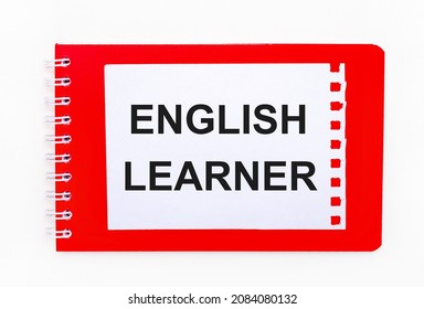 On A White Background - A Bright Red Notebook On A Spiral. On It Is A White Sheet Of Paper With The Text ENGLISH LEARNER