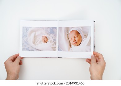 On A White Background, Hands Flip Through A Photobook From A Home Family Photo Shoot With A Newborn Child. Traditions To Make A Photo Album And Print Photos From Important Moments Of Life.