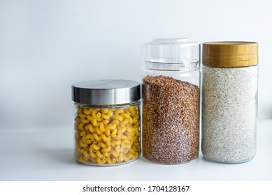 on a white background in jars and in packages different cereals, flour, pasta, stocks