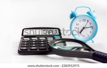 On a white background lies a calculator with the text on the CAPEX display. Business and financial concept