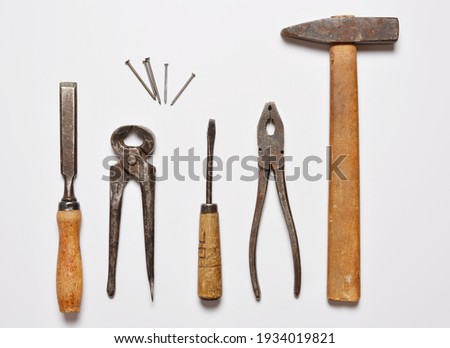 on a white background old often used hand tools hammer and nippers, pliers nails and chisel. flat lay. copy space.