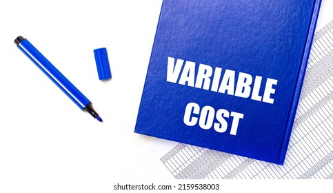 On A White Background Reports, A Blue Pen And A Blue Notebook With The Text VARIABLE COST. Business Concept. Banner