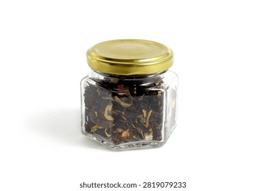 On a white background there is one glass jar of black tea with dry leaves and dried fruits.