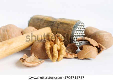 On a white background, a walnut is split with a hammer
