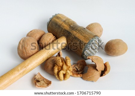 On a white background, a walnut is split with a hammer