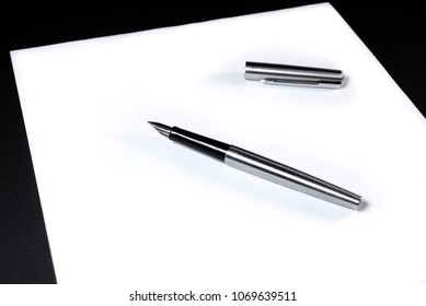 On a white sheet of paper is an ink pen with a cap. Black background