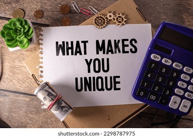 On a white surface, a yellow scroll of paper with the inscription - WHAT MAKES YOU UNIQUE. Business concept.