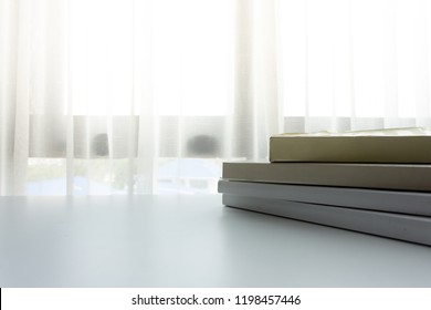 ฺBook on white table next to window wiht sunlight