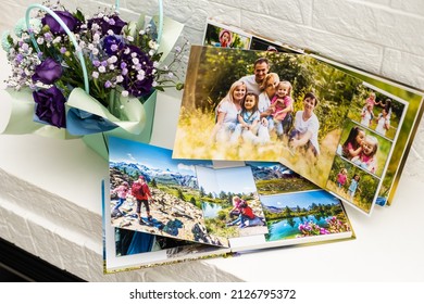 On White Table Open Photobook From Photo Shoot Of Family. Preservation Of Important Moments Of Life In Photo Album. Result Of Work Of Photographer And Designer. Polygraphy.